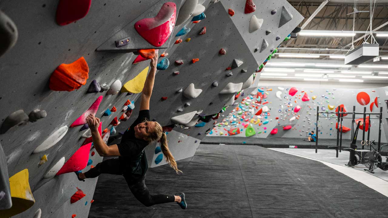 Lattice coach Jen Wood, trying different styles of climbing, on this over hanging sloper problem. 