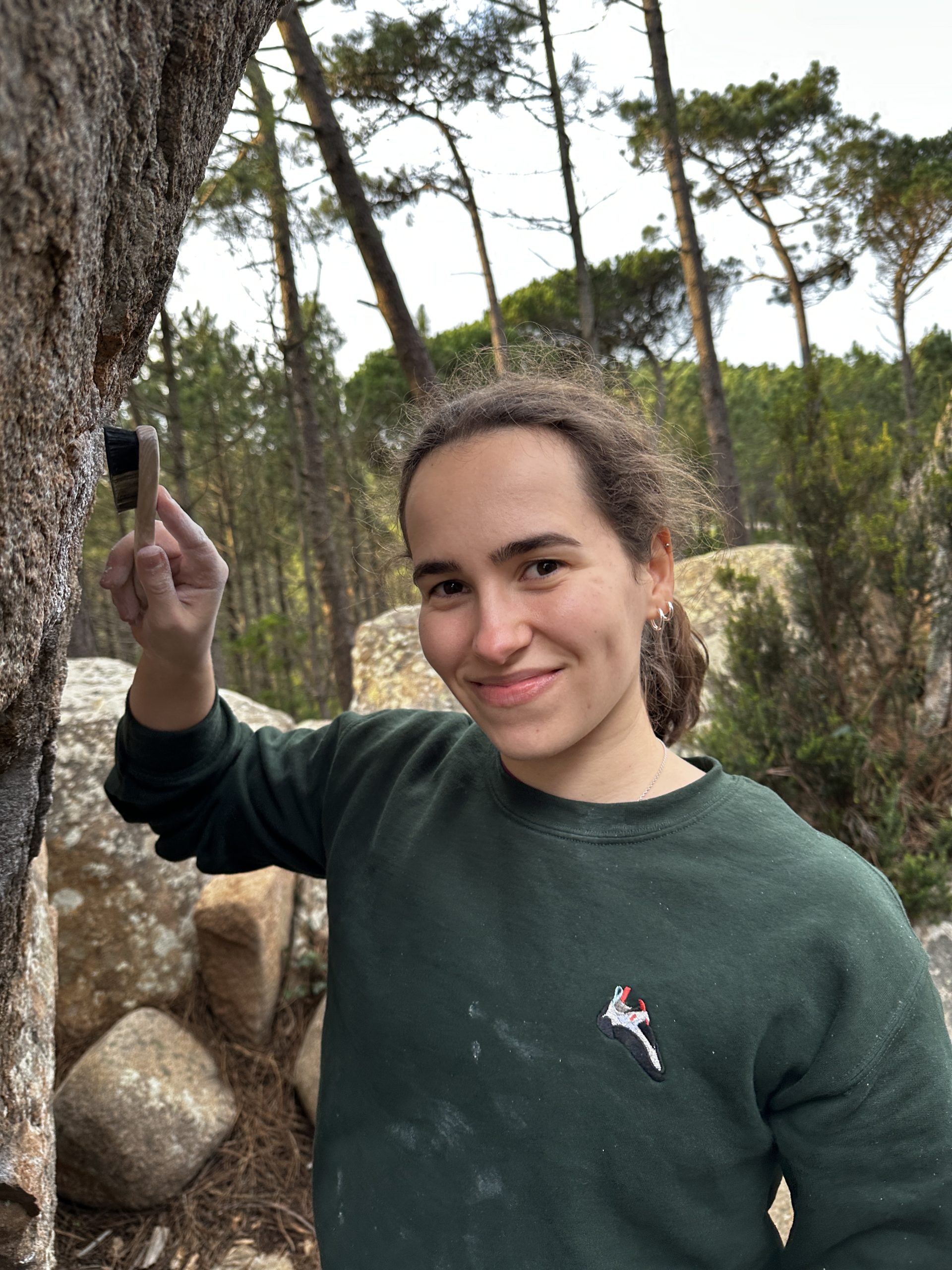 Teresa Coimbra smiling about to brush ticks off her boulder