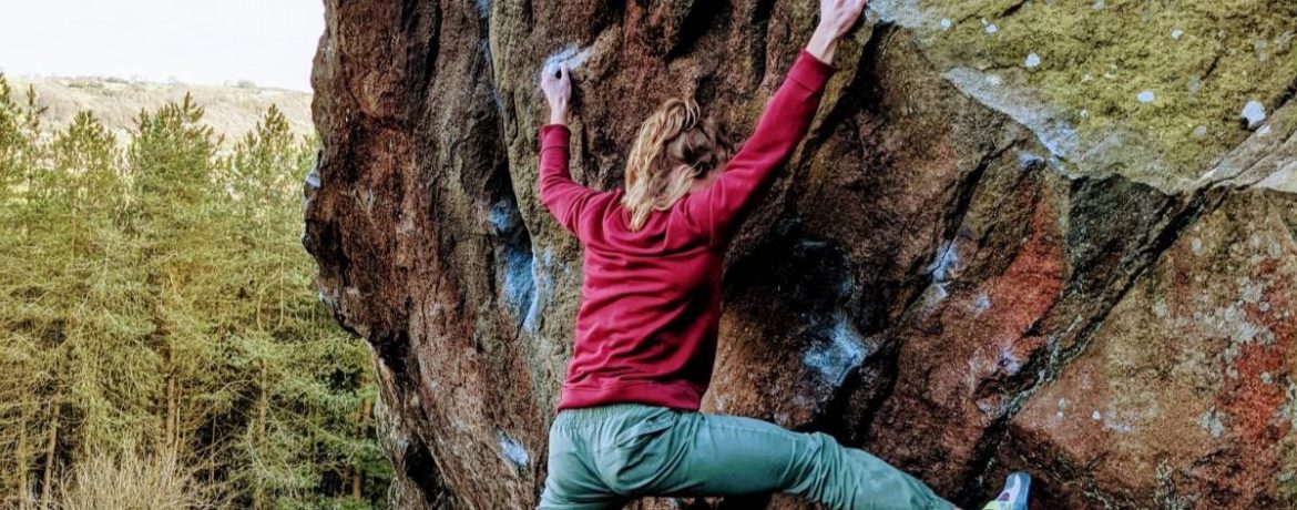 Lattice Coach, Maddy Cope, climbs a boulder outdoors