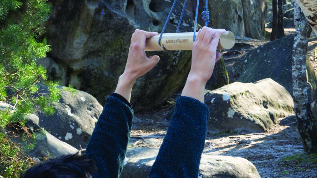 Climber warming up at the crag, with a mega bar portable hangboard. 