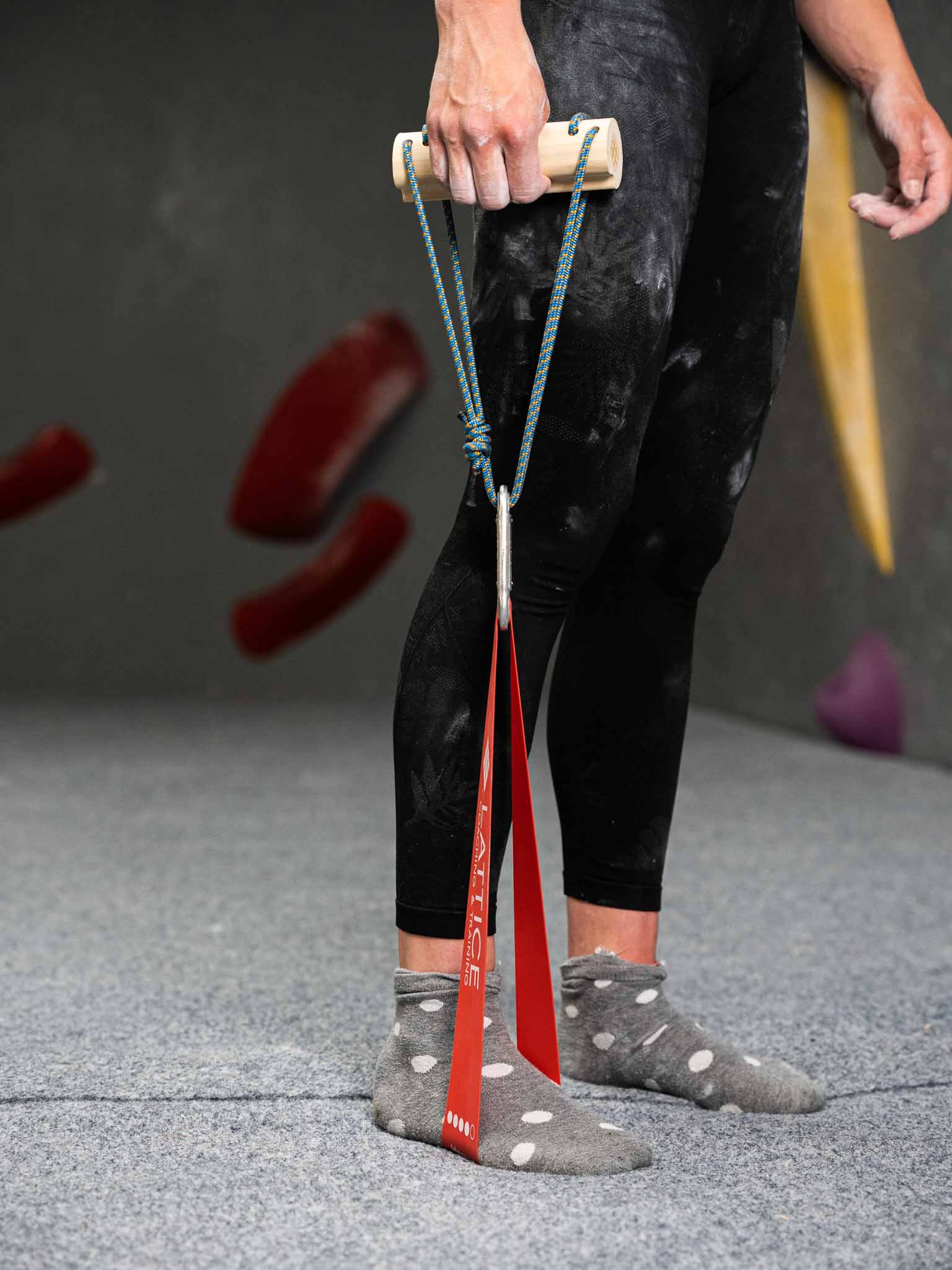 A climber pulls up a mini bar connected to a resistance band