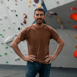 A climber with a busy schedule stands hands on his hips looking stressed